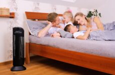 Oczyszczacz powietrza Ionic-CARE v ložnici vedle postele ve które si povídají matka, otec a jejich 2 malé děti, barva černá