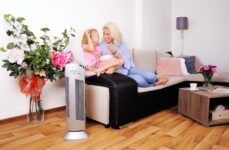 Oczyszczacz powietrza Ionic-CARE v obývacím pokoju vedle pohovky, na które relaxuje maldá maminka se svou dcerou, barva stříbrná